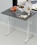 No Fuss Manual Crank Standing Desk That Dials Height Quick For Smooth Sit To Stand Workstation Killer Ergonomic Computer Desk For Tight Quarter Home Office Setup In Modern Charcoal Gray with office supplies on top.