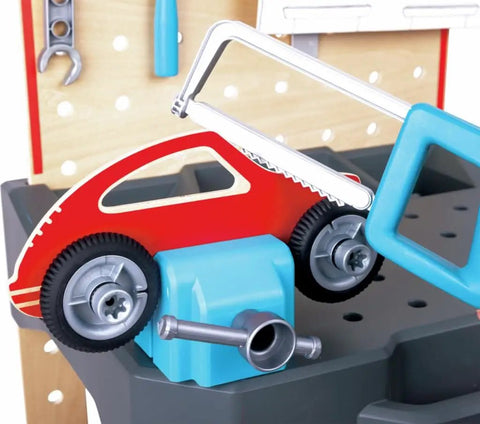 Vehicle Service And Repair Workbench Play Set With Realistic Tools For Young Builders Includes Drill Hammer Saw Wrench Tape Measure Bench Vice Gears Car Bodies Nuts And Bolts And Cardboard Garage Scene showing a saw cutting a toy car.