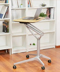 Hassle Free Pneumatic Sit Stand Laptop Desk Cart With Smooth Lever Adjustments Solid Rolling Ergonomic Mobile Workstation And No Fuss Stability For Home Office Study, featuring a laptop on a wooden top in a cozy room.