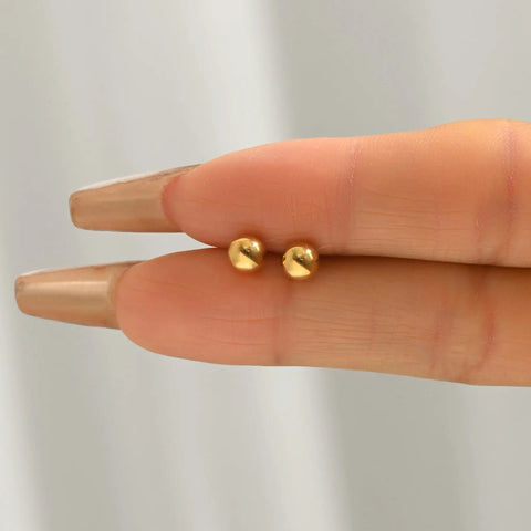 Gold Ball Stud Earrings For Women, 18K Gold Plated Stainless Steel Hypoallergenic Round Ball Studs, 2mm 3mm 4mm 5mm Size Set, Waterproof And Non Fade, Simple Yet Dope Everyday Jewelry. Two gold ball studs held between fingers.