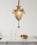 vhhob French Light Luxury Crystal Pendant Lamp Ceiling Hanging Fixture hanging above a marble table with glasses and fruit bowl.
