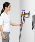 Woman using V15 Detect Total Clean Extra Refurbished Premium Vacuum Cleaner With Laser Dust Detection on white wall mount