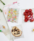 Clear 4x4 Inch Resealable Cookie Bags, 200 Pack, Self Sealing Cellophane Bags For Cookies, Candy, Treats, Favors, Jewelry, And Gift Wrapping, Thick 2.8 Mil For Premium Packaging displaying colorful candy, tomatoes, and a cookie.
