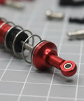 Close-up of a red metal shock absorber from the Milageto Industrial RC Steering Linkage Kit for WLtoys 12429.