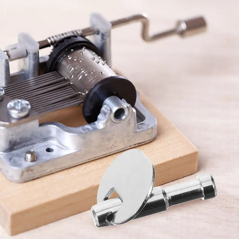 Music Box Winding Key Replacement Round Handle 1.57 Inch for Standard Movements shown with music box part on wooden base