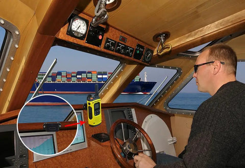Boat dashboard with heavy duty handheld radio holder for walkie talkie and speaker mic mounted, view of cargo ship outside window.