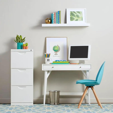 Modern home office setup with white desk, computer, and shelves, emphasizing bright, minimalist design and vibrant colors in decor.