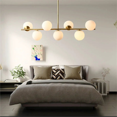 Groovy Mid Century Modern Pendant Light Set Featuring Sleek Glass Globes and Gold Finish over a stylish bed and decor.