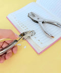 Person using Compact Single Hole Punch Metal Circle Punch for Scrapbooking and Office Use on notebook, 6mm hole puncher visible.