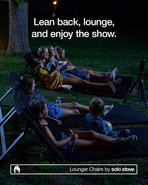 People lounging on adjustable chaise lounge with 2 inch foam pad and portable carry case during outdoor movie night.