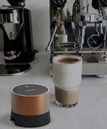 Smart Electric Coffee Tamper With 20 Level Adjustable Pressure And Precision Depth Control Featuring Steady Force For Flavor Packed Espresso Shots on counter with coffee cup.