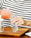 Person pouring liquid into a glass jar while using a Slick Replacement Soap Pump Head for Liquid Soap and Lotion Dispensers.