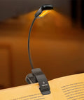 Amber Rechargeable Book Light With Blue Light Blocking for night reading, clipped onto a book, showing warm 1600K glow.