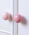 Totally Fresh Ceramic Ball Cabinet Knob Lemon Yellow Single Hole Drawer Pull For Bedroom Dresser And Kitchen Cupboard Lowkey Perfect Hardware Upgrade That Hits Different close-up of pink ceramic knobs on white cabinetry.