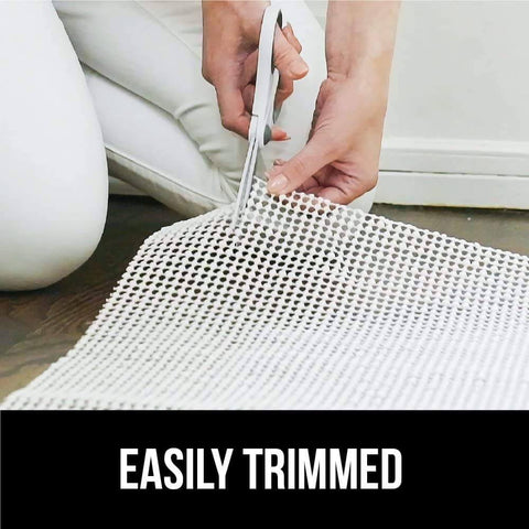 Person trimming Extra Strong Rug Pad Gripper 2x4 Ft for Hardwood Floors and Carpets, slip resistant, dual sided grip pad with scissors.