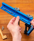 Hands adjusting Cabinet Hardware Jig And Pull Drill Guide Pro For Easy Install, Knob And Handle Hole Locator on a wooden surface.