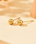Gold Ball Stud Earrings For Women, 18K Gold Plated Stainless Steel Hypoallergenic Round Ball Studs, 2mm 3mm 4mm 5mm Size Set, Waterproof And Non Fade, Simple Yet Dope Everyday Jewelry. Two gold ball studs on a light background
