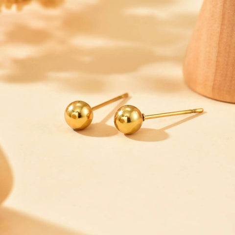 Gold Ball Stud Earrings For Women, 18K Gold Plated Stainless Steel Hypoallergenic Round Ball Studs, 2mm 3mm 4mm 5mm Size Set, Waterproof And Non Fade, Simple Yet Dope Everyday Jewelry. Two gold ball studs on a light background