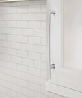 Side view of Cyprus Six And Five Sixteenths Inch Center To Center Polished Chrome Cabinet Pull installed on white cabinet