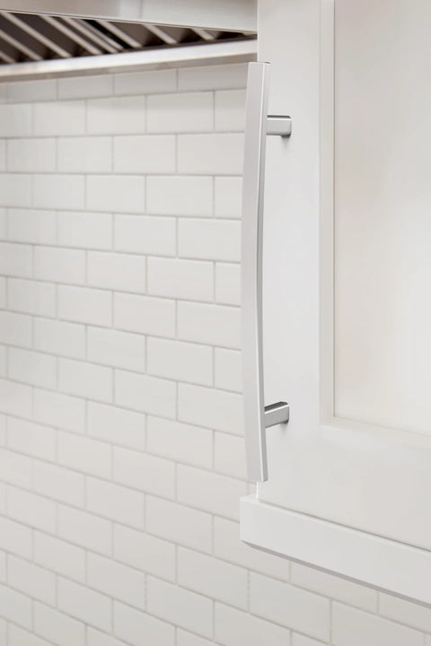 Side view of Cyprus Six And Five Sixteenths Inch Center To Center Polished Chrome Cabinet Pull installed on white cabinet