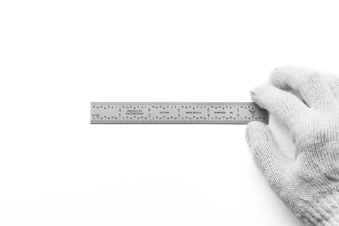 Dead Nuts Accurate Six Inch Metal Ruler Featuring Sharp Etched Scale Markings Built From Fully Hardened Carbon Steel With Sleek Chrome Plating held in a gloved hand.