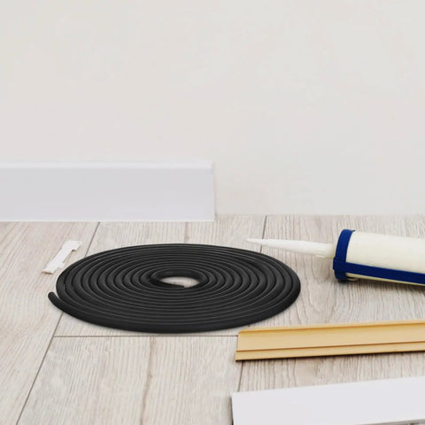 Heavy Duty Rubber Caulk Saver Strip For Concrete Joints Built Nails Tough Hella Flexible Black Weatherproof Wall Door Gap Sealer Universal Crack Stopper Five Meter Roll coiled on wooden floor with caulk gun.
