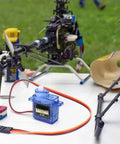 Four Pack 9g Micro Servo Motors For Arduino Projects with Metal Gears on table near RC helicopter