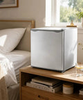 1.1 Cu Ft Compact Mini Freezer Solid Upright Build placed beside a bed in a cozy room, ideal for dorms and small spaces.