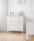 White dresser with three drawers and black knobs, decorated with toys and framed art in a bright room.