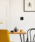Smart Thermostat T5 Black ENERGY STAR Certified in modern dining room with chairs, table, and wall art, compatible with Alexa and HomeKit.