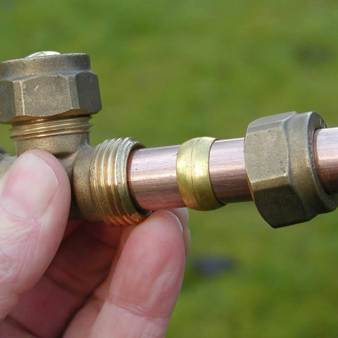 Brass compression fitting with 1/4" tube OD, ferrule sleeve on copper tube; close-up view