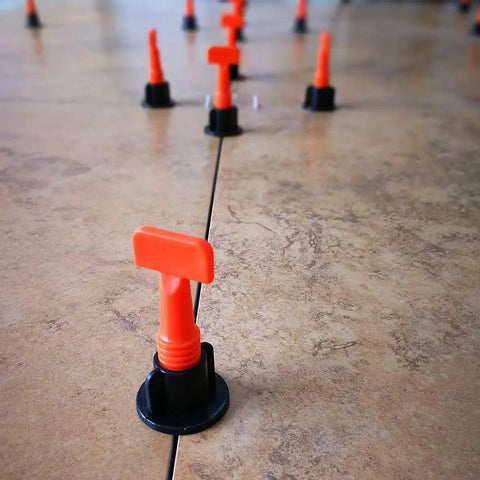 Tile Leveling System Kit 1/16 Inch Reusable for DIY and Pros showing orange levelers and spacers on tiled floor
