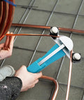Person using the Duratech Heavy Duty Ratcheting Tube Bender Kit to bend copper tubing on a workshop floor.