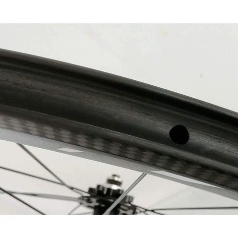Close-up of a 700C road carbon fiber fat ring disc brake wheel set rim with 50mm deep UD matte finish, visible spoke and hub.