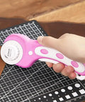 Hand holding pink 45mm Rotary Cutter With 5 Extra Blades, Ergonomic Grip, for Fabric Leather Crafting Sewing and Quilting