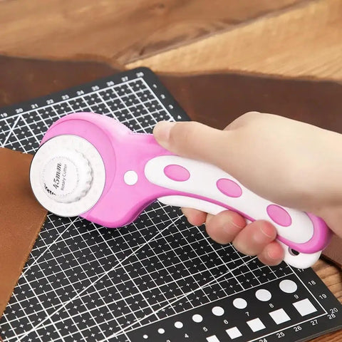 Hand holding pink 45mm Rotary Cutter With 5 Extra Blades, Ergonomic Grip, for Fabric Leather Crafting Sewing and Quilting