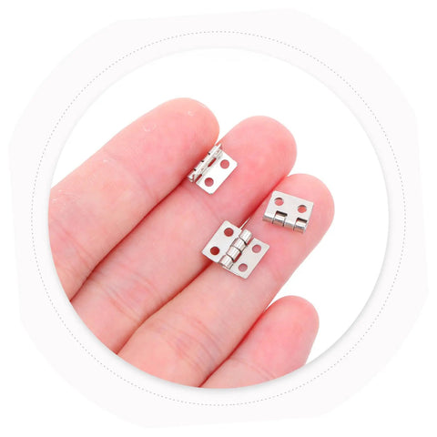 Copper Mini Hinges For Craft Projects And Jewelry Boxes, 100 Pack shown on fingertips, small 4 hole hardware for DIY trinket boxes.