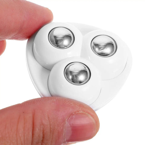 Close-up of 12pcs Self Adhesive Furniture Casters ABS Steel 360 Degree with shiny round wheels held between two fingers.