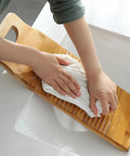 Person using No Sweat Bamboo Washboard For Hand Washing Clothes with a white cloth in a sink, showcasing non-slip grooves.