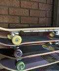 Stack of skateboards with various colored wheels against a brick wall