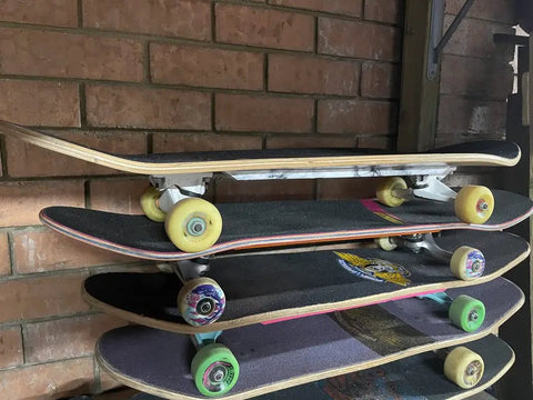 Stack of skateboards with various colored wheels against a brick wall