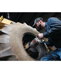 Pro Level One Inch Drive Air Impact Wrench used on a large tire for garage tasks, featuring a robust design for heavy-duty applications.