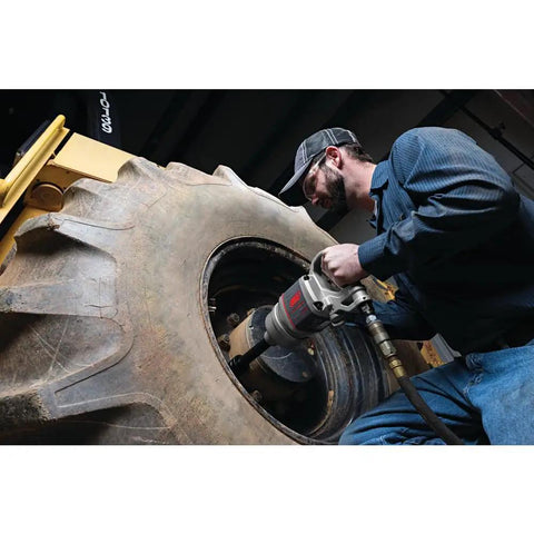 Pro Level One Inch Drive Air Impact Wrench used on a large tire for garage tasks, featuring a robust design for heavy-duty applications.