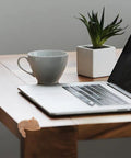 Desk with laptop and cup, featuring 4 Pack Silicone Corner Protectors For Furniture And Tables With Adorable Dog And Bear Designs Anti Collision Safety Guards