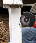 4.5-inch cut-off wheel on an angle grinder cutting a white wooden post; gloved hands