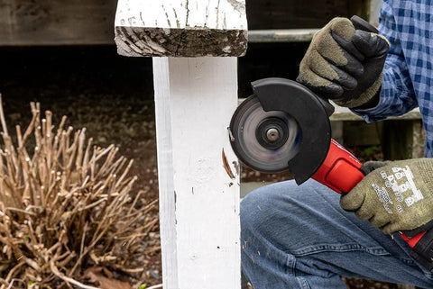 4.5-inch cut-off wheel on an angle grinder cutting a white wooden post; gloved hands