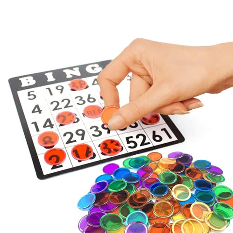 Hand placing orange marker on bingo card with Magnetic Bingo Set With 100 Orange Plastic Markers For Math Counting And Science Exploration Kid Friendly STEM Kit For Classroom And Family Game Night Hands On Learning Sorting And Creative Play Fun visible.