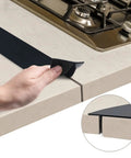 Person installing Stove Gap Cover 21 Inch Silicone Gap Filler for Kitchen Counter and Stove Heat Resistant Easy Clean Keeps Crumbs and Spills Out Black 2 Pack