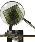 Adjustable Helping Hand With Magnifying Glass 2x, Dual Alligator Clamps holding a PCB on black cast iron base for soldering and repair