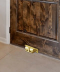 Adjustable Roller Ball Door Catch For Cabinets, Closets, And Wardrobes, gold brass latch installed on wood door, floor view